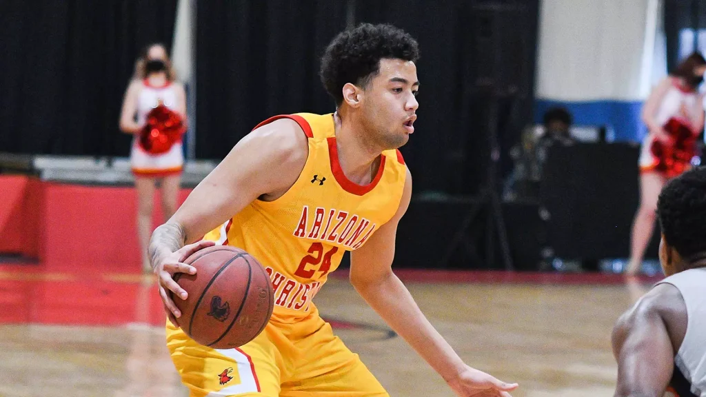 Basketball player in a yellow Arizona jersey dribbles the ball during a game on a gym court, focused on advancing toward the basket.