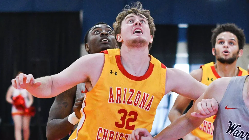 Arizona basketball player wearing number 32 in a yellow jersey reaches forward with arms outstretched during a fast-paced game, closely pursued by teammates behind him.