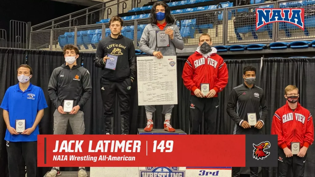 Wrestlers pose on a podium at a NAIA wrestling event, holding plaques and certificates, with a large red banner reading 'Jack Latimer | 149 NAIA Wrestling All-American' in front.