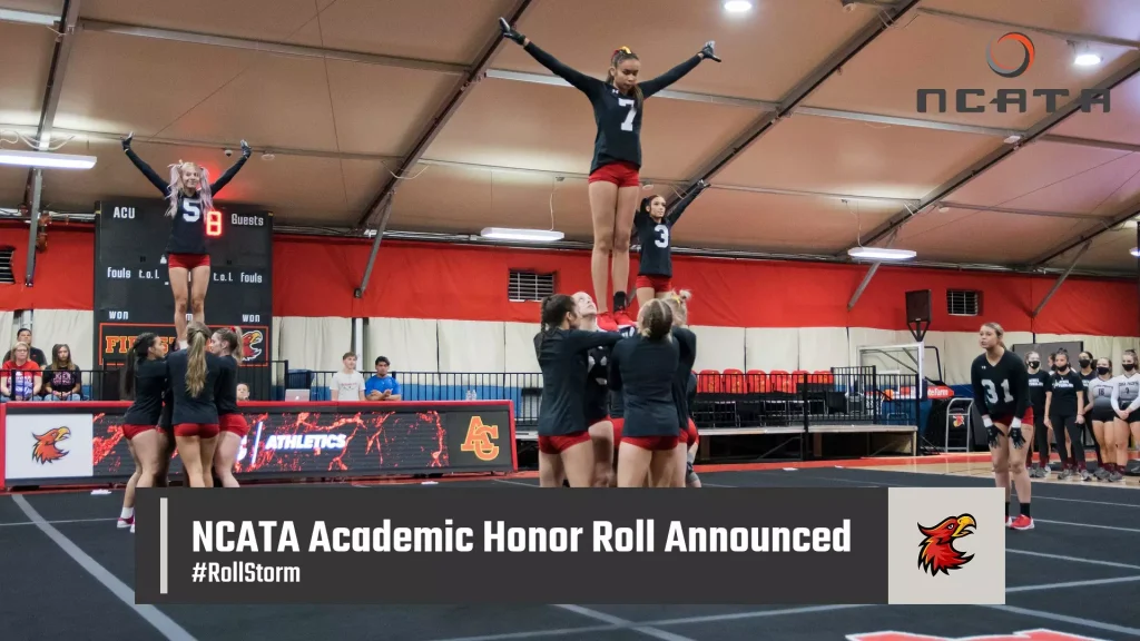 Cheerleaders perform a pyramid stunt on a gym mat as teammates look on; scoreboard and NCATA logo in the background.