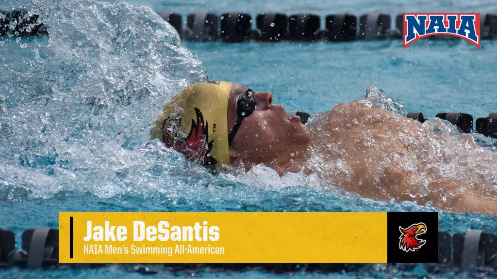 Swimmer in a yellow cap goggles racing in a pool; NAIA logo visible in the top-right corner.