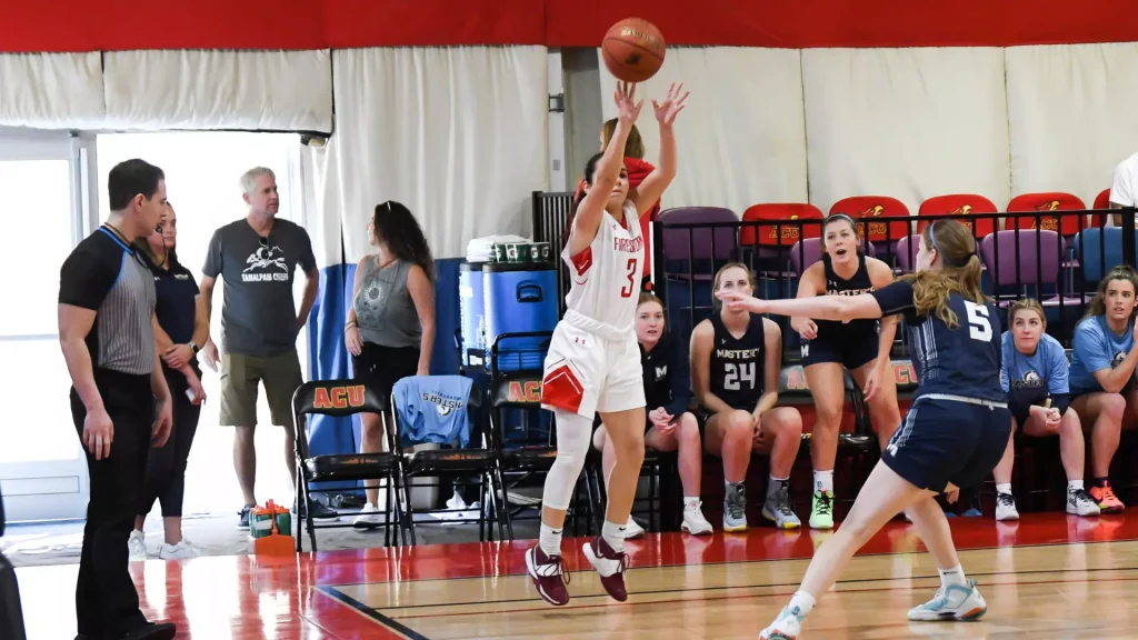 White-team player #3 leaps for a jump shot as teammates and coaches watch from the bench in a gym.
