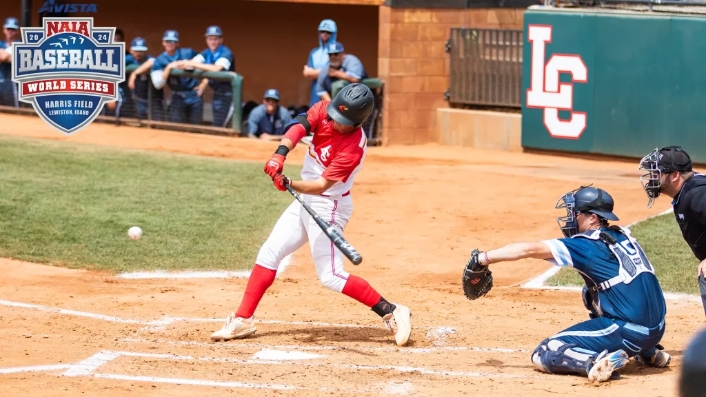 Baseball batter in red and white swings at a pitch, with a blue-gear catcher behind and a tournament logo to the left.