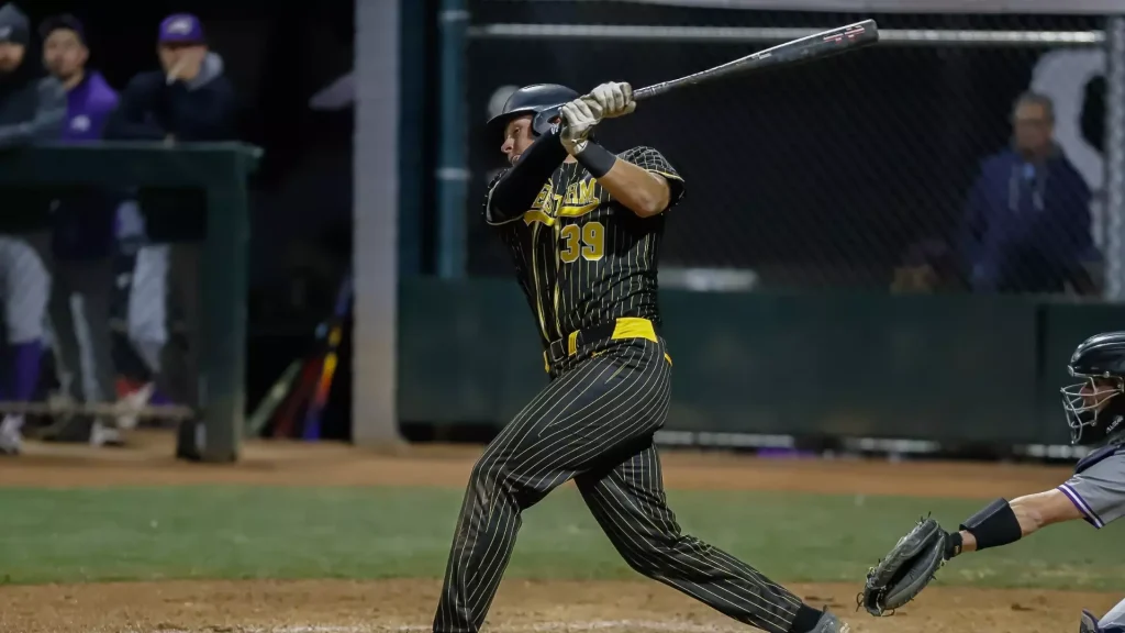 Baseball batter in black pinstripe uniform (number 39) swings a bat during a at-bat, helmet on, with catcher visible to the right.