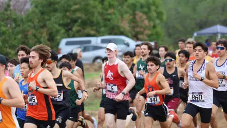 Group of runners competing in a race on a paved road, wearing numbered bibs and colorful athletic gear.