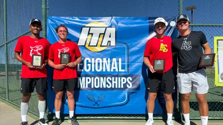 Four players pose with awards in front of a banner reading ITA Regional Championships at a tennis event.